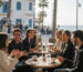 Group of young adults practicing Hebrew conversation outdoors at a café by the beach – Modern Hebrew course atmosphere
